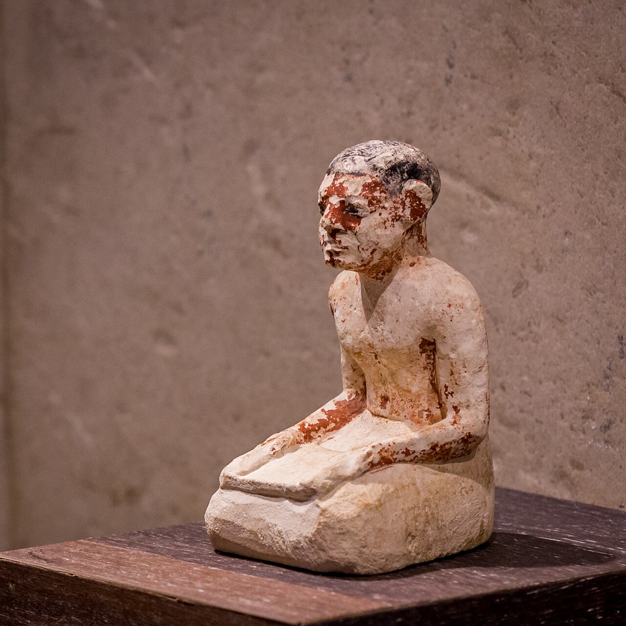 Portrait 
        statuette of an 
        Egyptian scribe sitting on the floor